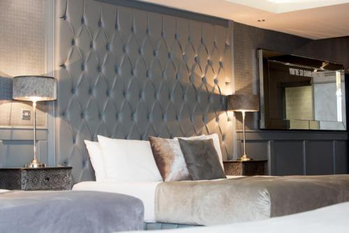 a bedroom with a bed and two lamps and a wall at The Shankly Hotel in Liverpool