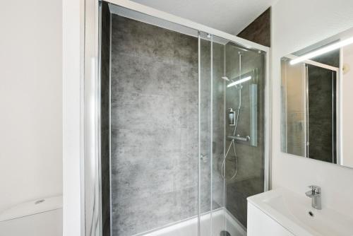 y baño con ducha y puerta de cristal. en All Suites La Teste – Bassin d’Arcachon, en La Teste-de-Buch