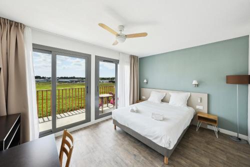 a bedroom with a bed and a table and a balcony at All Suites La Teste – Bassin d’Arcachon in La Teste-de-Buch