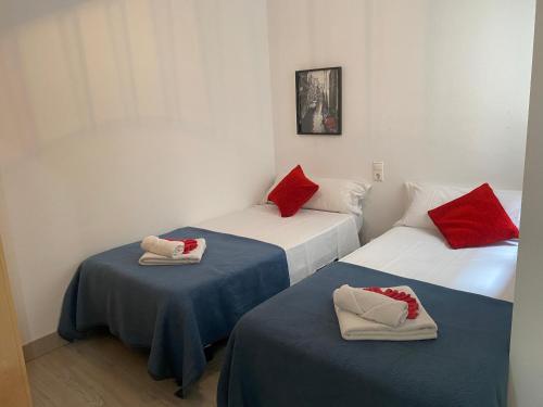 2 Betten in einem Zimmer mit roten und weißen Kissen in der Unterkunft Homely Apartments Las Salinas in Torrevieja