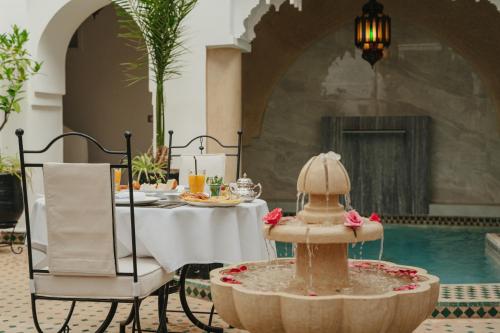 ein Esszimmer mit einem Tisch und einem Brunnen in der Unterkunft Riad Dar Dialkoum in Marrakesch