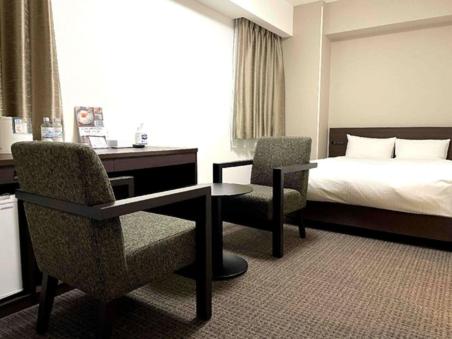 una camera d'albergo con letto, scrivania e sedie di HOTEL GLAN Y's KUMAGAYAEKIMAE a Kumagaya