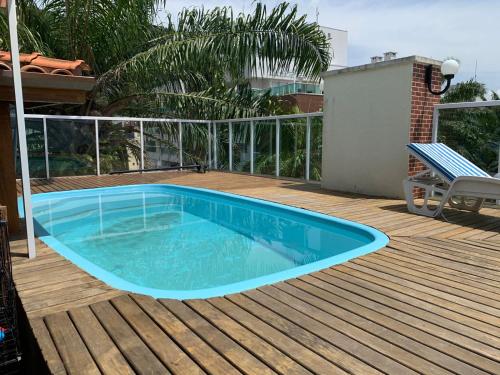 uma piscina azul num deque com um banco em Cobertura Duplex Premium em Ubatuba