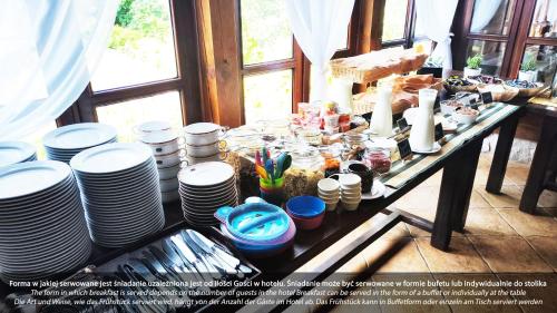 a table with a bunch of plates on it at Hotel Dworek Wapionka in Górzno