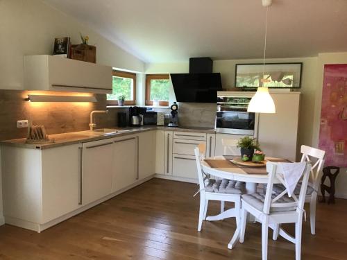 a kitchen with white cabinets and a table and chairs at Moorgalerie in Edewecht