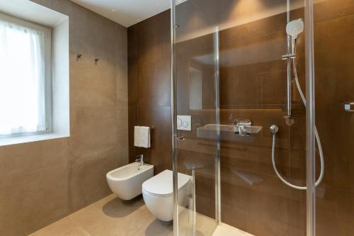a bathroom with a toilet and a glass shower at Hotel Lido - slow & natural living in Molveno