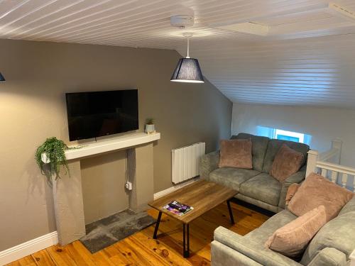 a living room with a couch and a flat screen tv at 2 Bed Townhouse Eyre Square City Centre in Galway