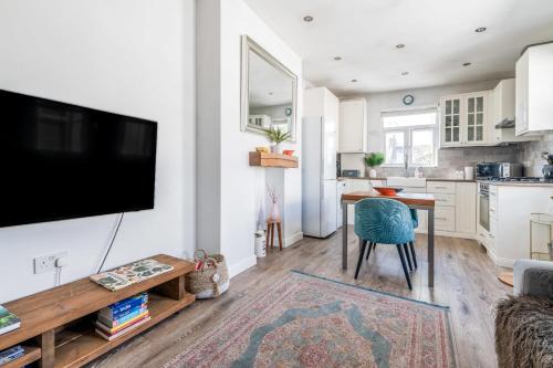 a living room with a table and a tv on a wall at Chic and Cheerful Flat in Willesden Green in London