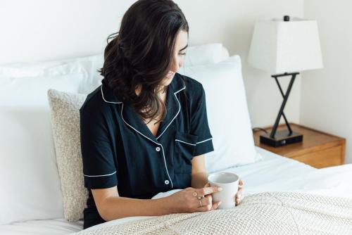 a woman sitting on a bed holding a coffee mug at Mint House St. Petersburg - Downtown in St Petersburg