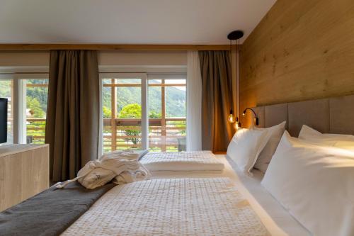 a bedroom with two beds and a large window at Hotel Lido - slow & natural living in Molveno