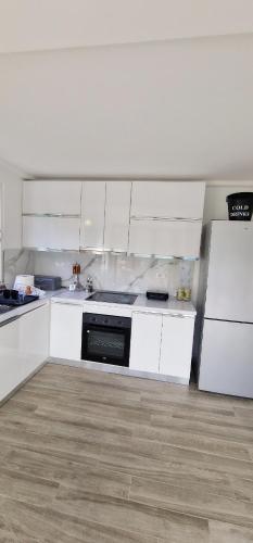 a white kitchen with white cabinets and a refrigerator at Koman Paradise by Romina in Shkodër