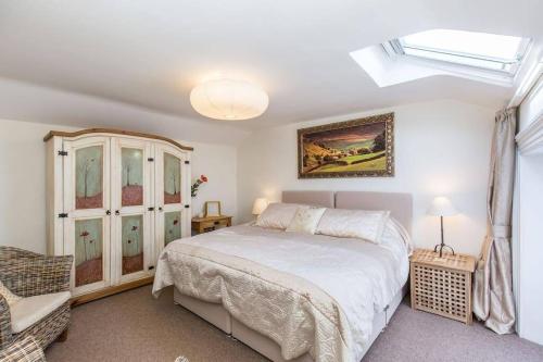 a bedroom with a large white bed and a window at Fern Hse Grassington; central yet quiet & parking in Grassington