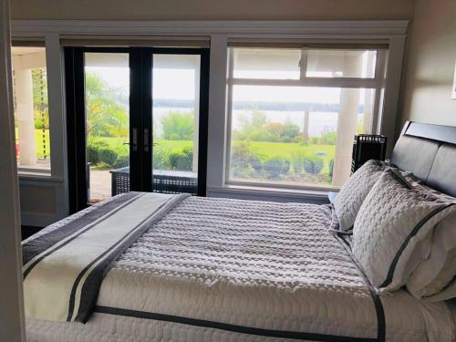 Saanichton的住宿－Saanichton Waterfront 2BR suite with superb views，一间卧室设有一张大床和两个窗户