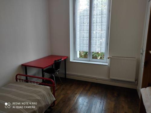une pièce avec une table et une table rouge et une fenêtre dans l'établissement Bel appartement proche toutes facilités, à Nancy