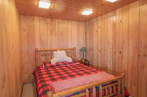 a bedroom with a bed in a wood paneled room at Big Wood Pines - Relaxing home with a large fenced yard for your furry friends to enjoy! in Big Bear City