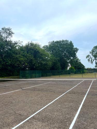 an empty tennis court with trees in the background at HOTEL BOUTIQUE VILLA DEL MARQUÉS in Muros de Nalón