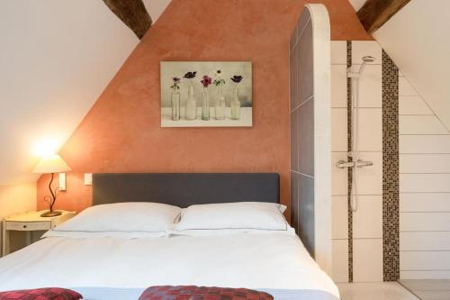 a bedroom with a white bed and flowers in vases on the wall at Gites de Climats de 3 à 6 personnes in Beaune