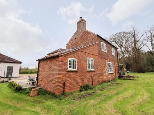 an old brick building in a grassy yard at Pat's Cottage in Market Rasen