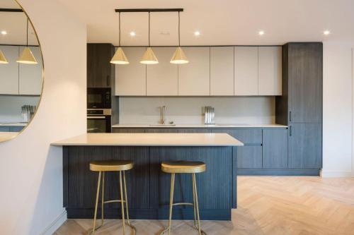 une cuisine avec des placards bleus et deux tabourets de bar dans l'établissement Huband Place, à Dublin