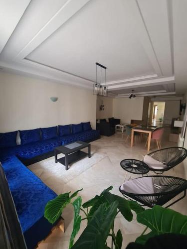 ein Wohnzimmer mit einem blauen Sofa und einem Tisch in der Unterkunft Immense appartement familial lumineux haut de l Agdal in Rabat