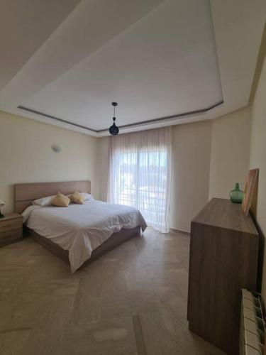 ein Schlafzimmer mit einem Bett und einem großen Fenster in der Unterkunft Immense appartement familial lumineux haut de l Agdal in Rabat