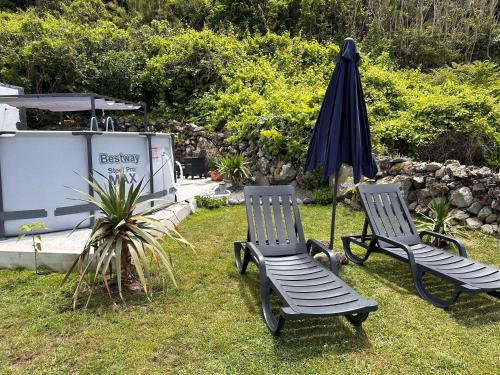 two chairs and an umbrella in a yard at Spot Milasmar in Faja Grande