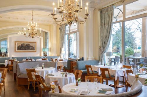 restauracja ze stołami i krzesłami oraz żyrandolem w obiekcie Beau-Rivage Palace w Lozannie