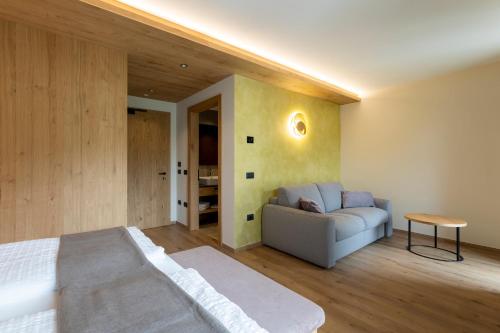 a bedroom with a bed and a couch in it at Hotel Lido - slow & natural living in Molveno