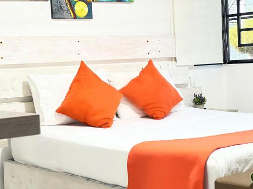 a bed with orange and white pillows on it at Fort House in Cali