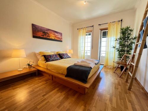 um quarto com uma cama grande e pisos em madeira em Yellow House Ericeira na Ericeira