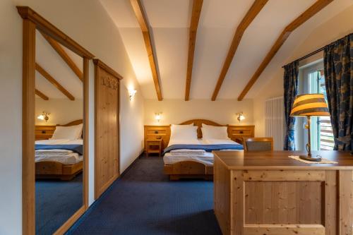 a bedroom with two beds and a desk in a room at Hotel Lido - slow & natural living in Molveno