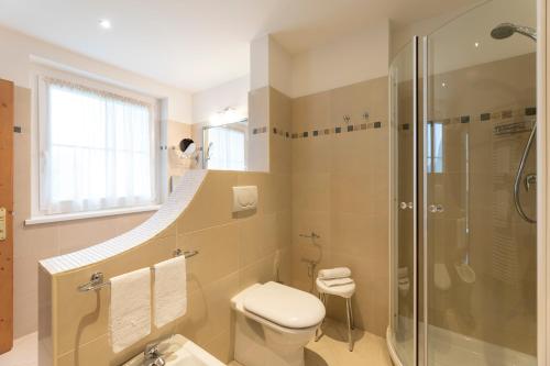 a bathroom with a shower and a toilet and a sink at Hotel Lido - slow & natural living in Molveno