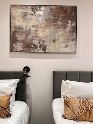 a painting above two beds with pillows in a room at Star London Finchley Road 1-Bed Sanctuary in London