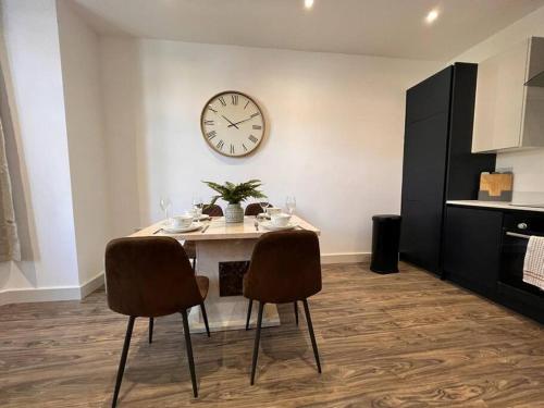 a dining room with a table and a clock on the wall at Star London Finchley Road 1-Bed Sanctuary in London