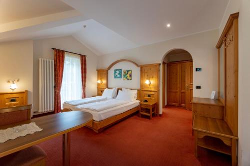 a hotel room with a bed and a desk in it at Hotel Lido - slow & natural living in Molveno