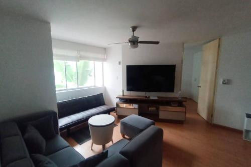 ein Wohnzimmer mit einem Sofa und einem Flachbild-TV in der Unterkunft Departamento para un buen descanso in Lima