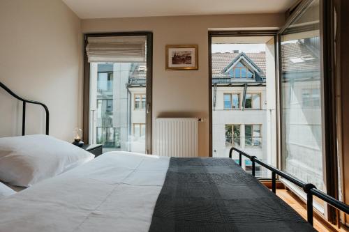 a bedroom with a bed and large windows at Plac Nowy - Beautiful view of the Old Town in Krakow