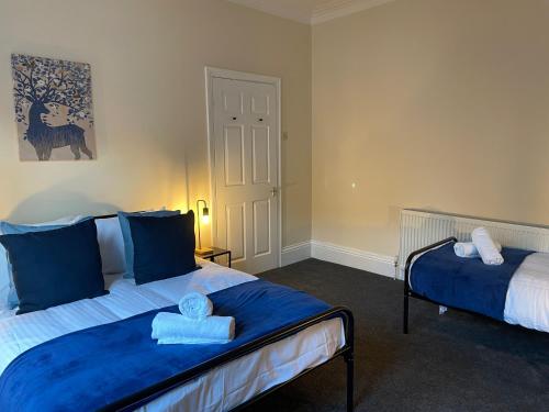 a bedroom with two beds with blue pillows at Howe - Newly refurbished 2 bedroom flat Free Parking in Gateshead