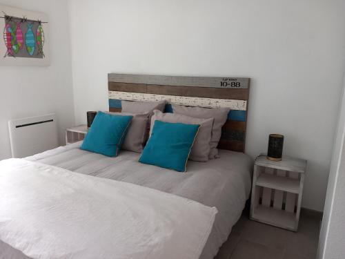 a bedroom with a large bed with blue pillows at le loft de la riviéra in Bénodet