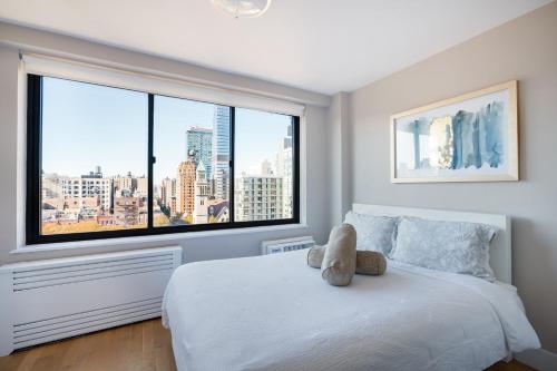 un osito de peluche sentado en una cama en un dormitorio con ventana en Apartment in Columbus Avenue, en Nueva York