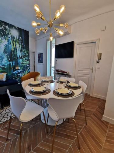 a dining room table with white chairs and a chandelier at Vista Monaco, 5mn walk to Monaco, Amazing view in Beausoleil