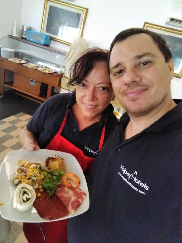 a man and a woman holding a plate of food at Hotel Rosy in Bellaria-Igea Marina