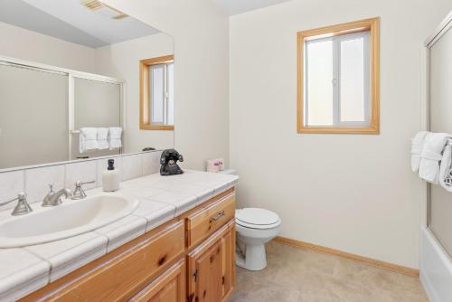 Baño blanco con lavabo y aseo en Papa Bear's Hideout - Dream Getaway with Hot Tub and Game Room!, en Big Bear Lake