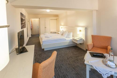 a hotel room with a bed and a chair at Hotel Magdalenenhof inklusive MeineCardPlus in Willingen