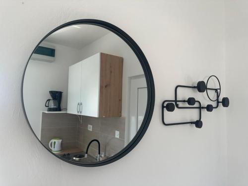 a mirror hanging on a white wall with a kitchen at Apartment Stanko in Ližnjan