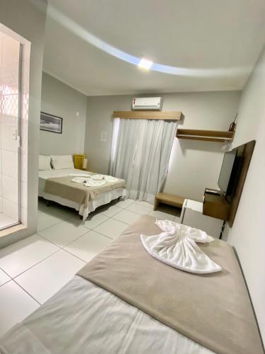 a hotel room with two beds and a television at Pousada Bonanza in Arraial do Cabo