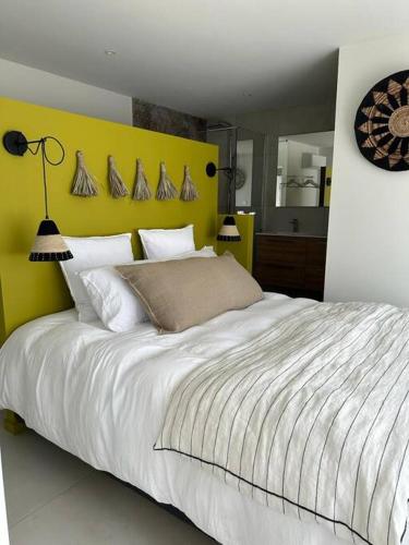 - une chambre avec un grand lit et une tête de lit jaune dans l'établissement villa avec piscine loft cabane, à Nîmes