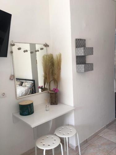 uno scaffale bianco con due sgabelli e uno specchio di Layla' s Petite Home a Città di Kos