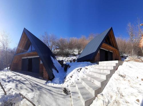 a log cabin with snow on the ground at Dawn Villas in Ferizaj