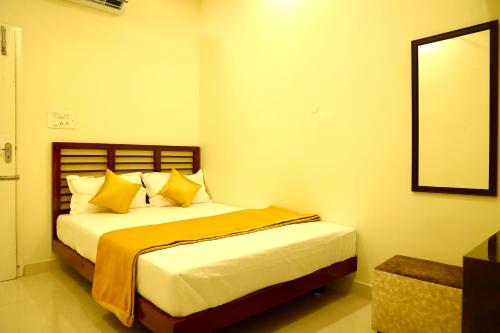 a bedroom with a bed with yellow pillows and a mirror at JACK'S DEN residency in Puducherry